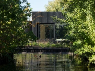 Une petite maison noire posée sur l'eau