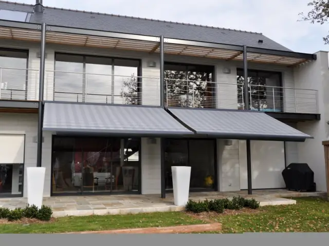 Des stores gris en camaïeu avec la toiture et la pergola - Un store de terrasse en harmonie avec la maison