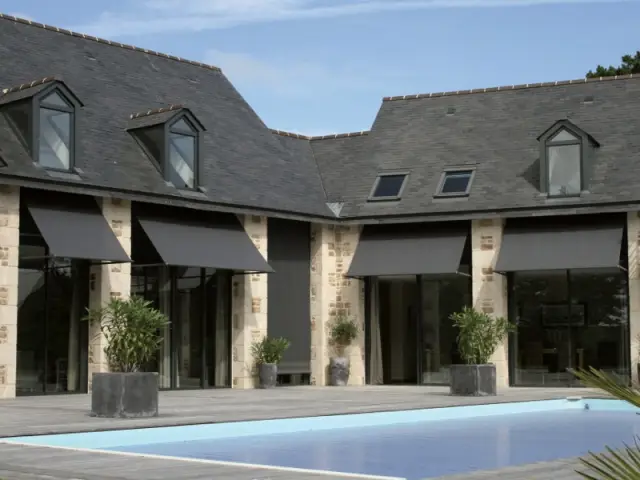 Des stores ardoise dans la continuité de la toiture - Un store de terrasse en harmonie avec la maison