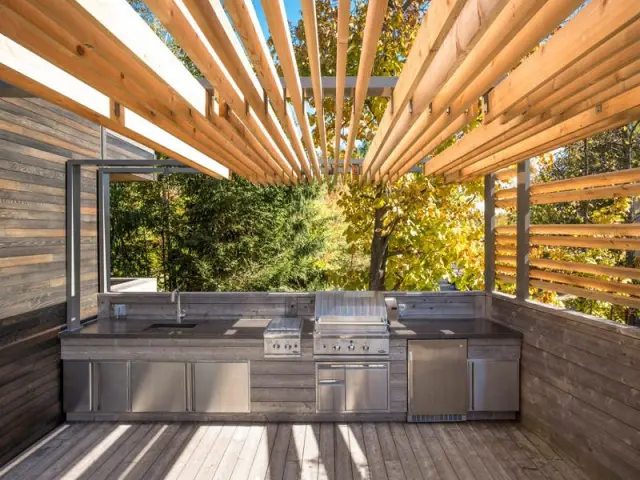 Une cuisine d'extérieur équipée aux teintes vieillies - Une terrasse en cèdre magnifie le paysage canadien