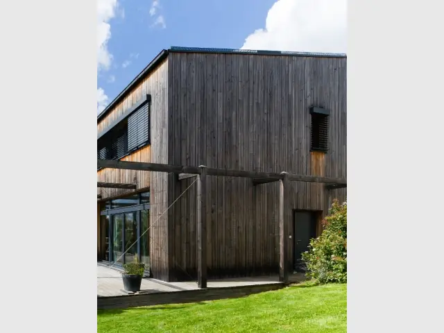 Une porte d'entrée dissimulée dans la façade de la maison passive - Une maison passive en bois gris au coeur des Yvelines