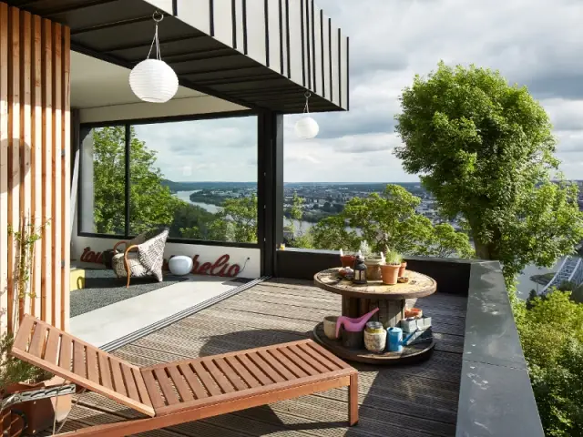 Une maison en zinc noir posée sur un mur en brique