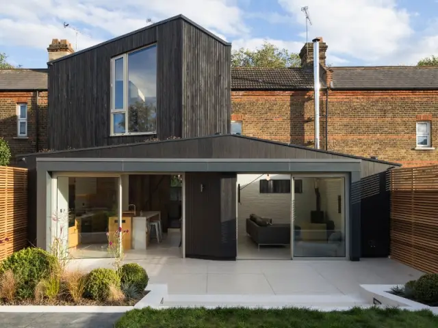 Une extension noire qui contraste avec la maison en brique