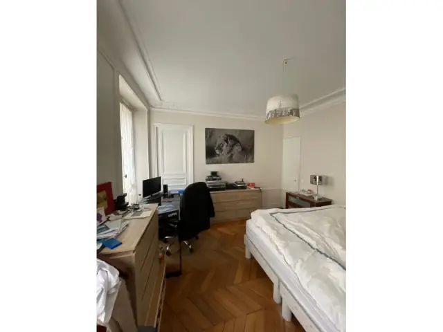 Une grande chambre avec deux fenêtres donnant sur rue